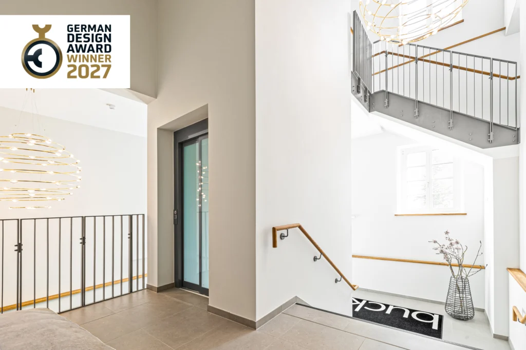 Treppenhaus der Heeresbäckerei Kassel mit Aufzug, Stahlgeländer, Eichenhandlauf und Lichtskulptur